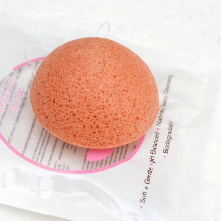 Rosa konjacsvamp som ligger ovanpå en produktförpackning.