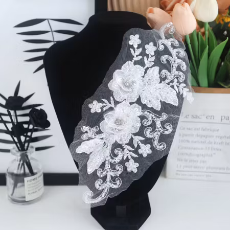 Vit spetsapplikation med paljetter och blommor
