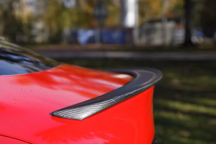 Performance spoiler i matt carbon fiber till Tesla Model S monterad på röd bil