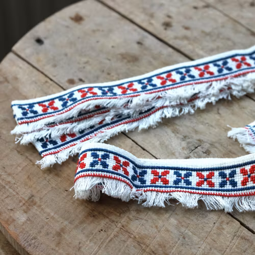 Hyllbård - Bård i rött och blått på vit väv.