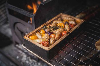 Salsiccia på färgglada grönsaker, tillagad i en Brick från Römertopf
