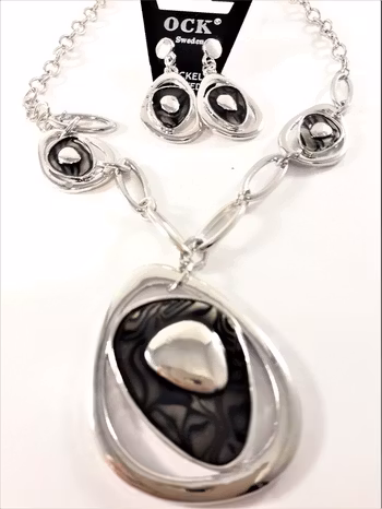 Silverfärgad halskedja med svarta detaljer samt matchande örhängen