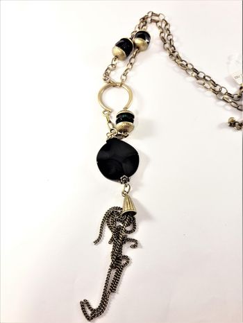 Detaljrikt halsband med kedja och många detaljer i svart och guldfärg