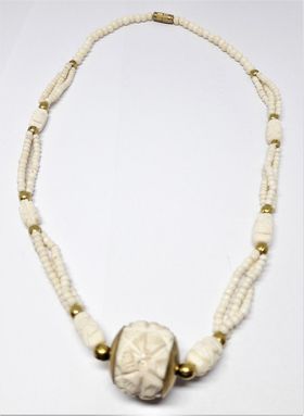 Halsband i ben med kulor i gul metall