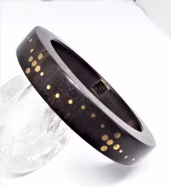 Stelt armband av trä med guldfärgat mönster