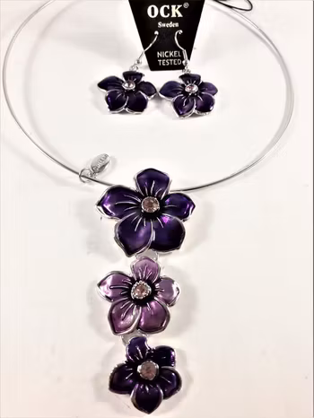 Stelt halsband med hänge av lila blommor samt matchande örhängen