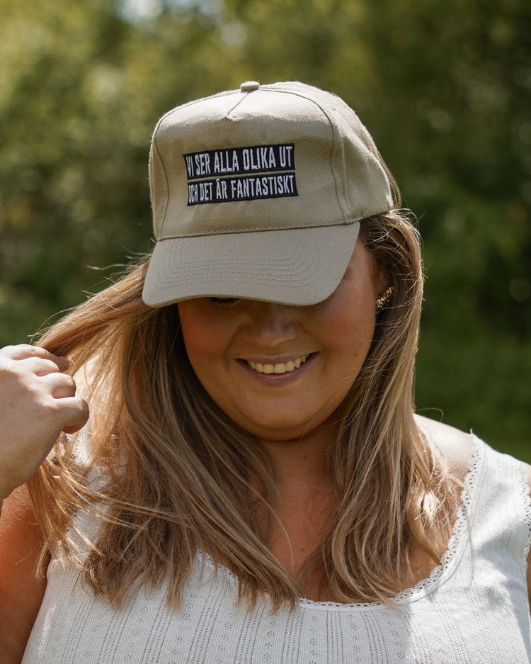 Beige keps "Vi ser alla olika ut och det är fantastiskt"