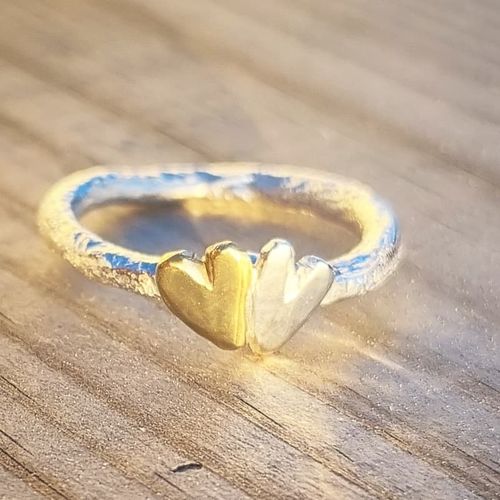 A sparkling and raw heart ring with a silver heart and a brass heart