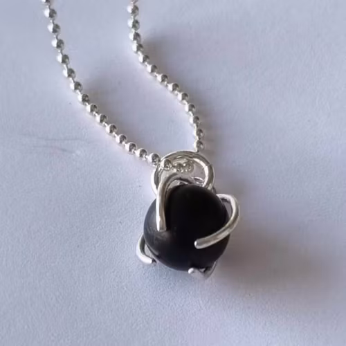 Ett fint halsband med en infattad rund svart sten, i äkta silver