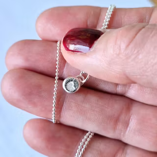 En fin handgjord berlock, silversmåtting med fossilsnäcka