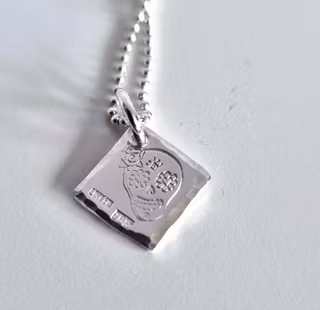 Ett fint silverhalsband med en döskalle i äkta silver HER på en silverbricka