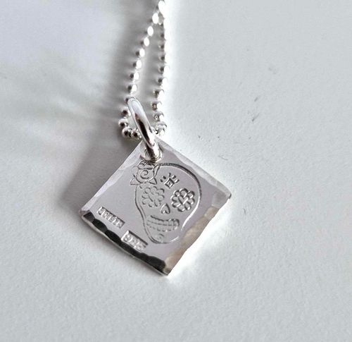 Ett fint silverhalsband med en döskalle i äkta silver HER på en silverbricka