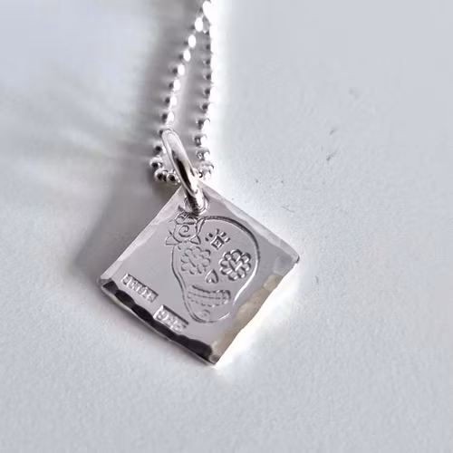 Ett fint silverhalsband med en döskalle i äkta silver HER på en silverbricka