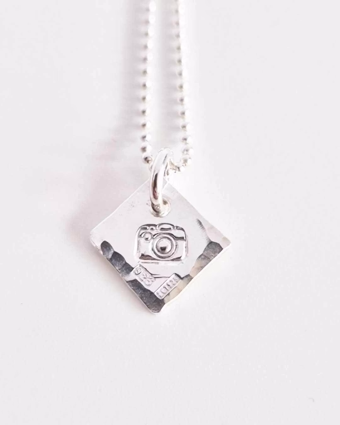 Ett fint silverhalsband med en kamera Fokus