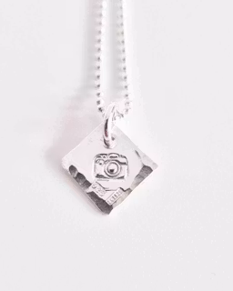 Ett fint silverhalsband med en kamera Fokus
