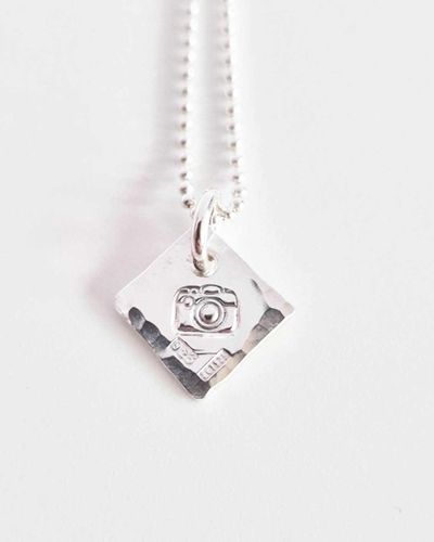 Ett fint silverhalsband med en kamera Fokus
