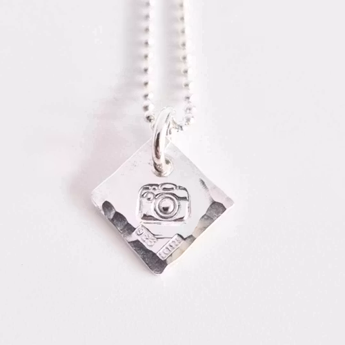Ett fint silverhalsband med en kamera Fokus
