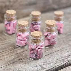 Thulit, små trumlade i glasflaska