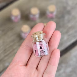 Thulit, små trumlade i glasflaska