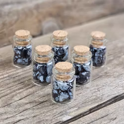 Snöflingeobsidian, små trumlade i glasflaska