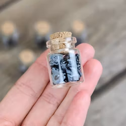 Snöflingeobsidian, små trumlade i glasflaska