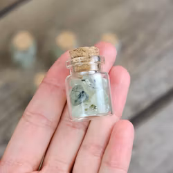 Prehnit, små trumlade i glasflaska