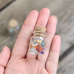 Stor mix av små trumlade i glasflaska