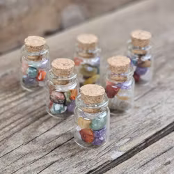 Stor mix av små trumlade i glasflaska