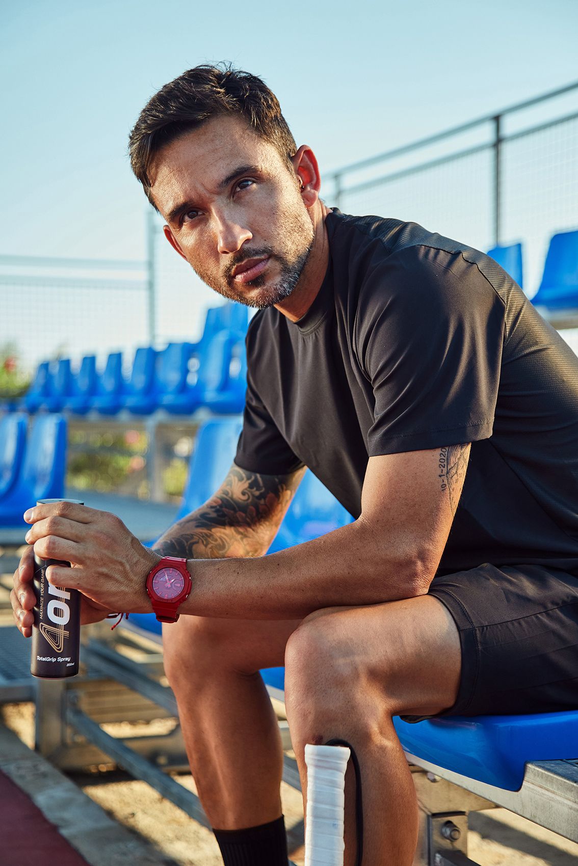 Pro padel player Daniel Sanyo Gutierrez sitting next to the padel court, holding 4on TotalGrip Spray.