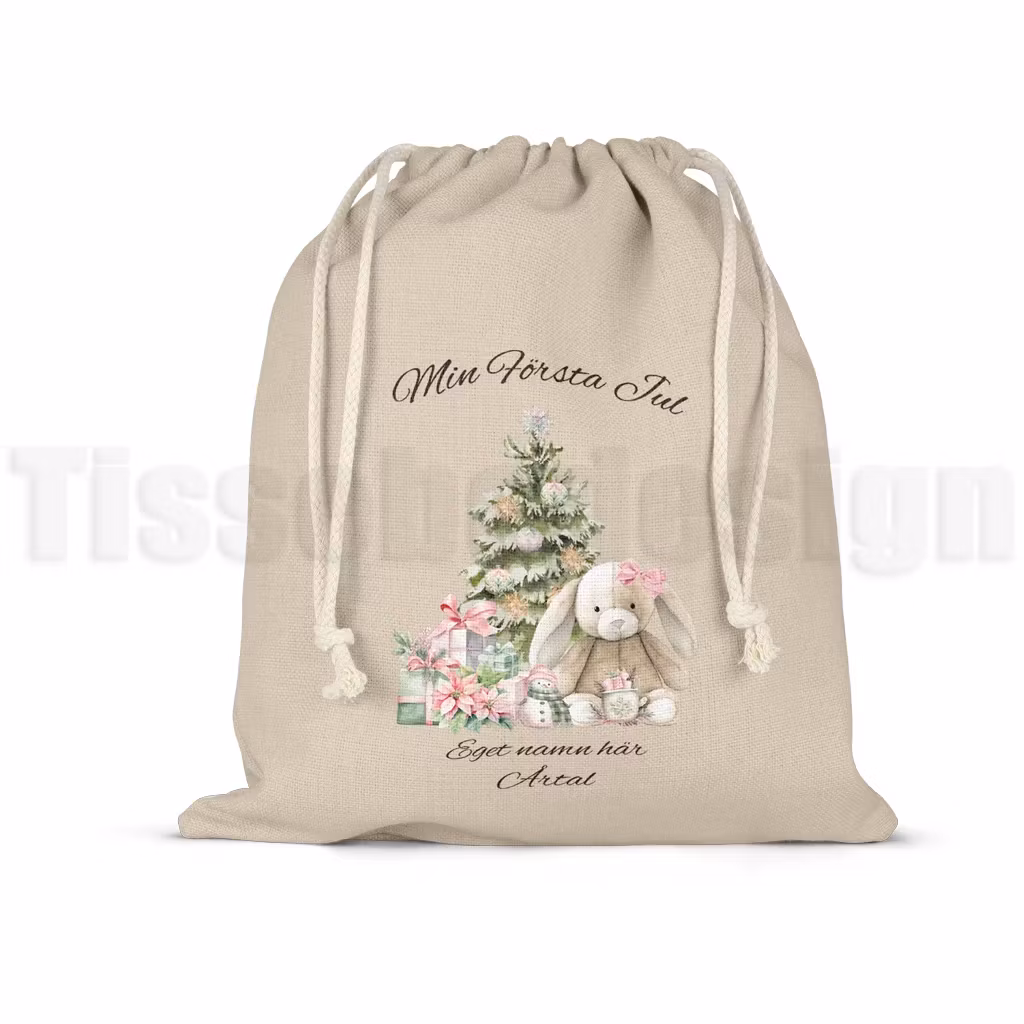 Julsäck med julgran, kanin och presenter med texten Min första jul