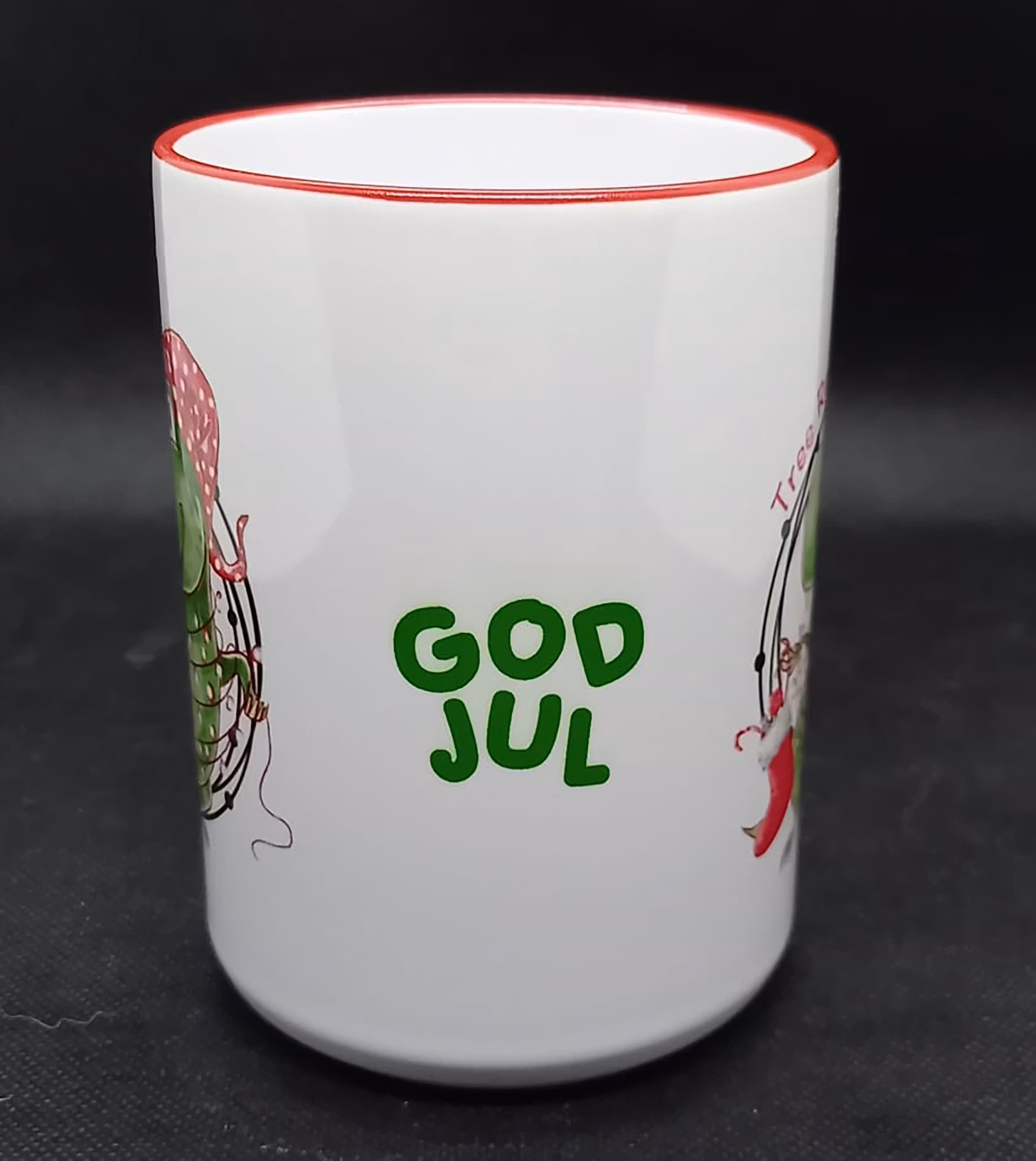 Julmugg med trycket 'Tree Rex', dinosaurie klädd som en julgran och texten god jul. Keramik, 450 ml, med rött handtag och kant.