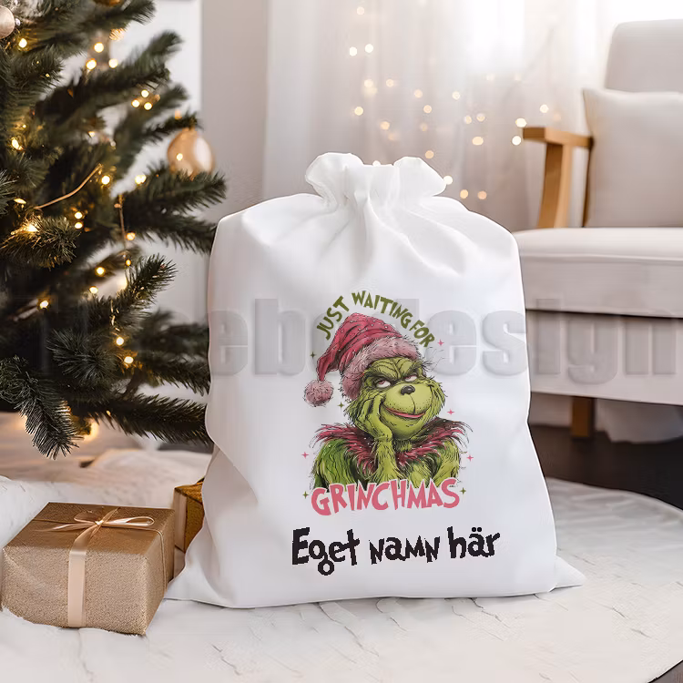 Vit julsäck i canvas med tryck Grinchen tjej och med texten Just Waiting For Grinchmas, med tryck på ena sidan av säcken och namn längst ner under motivet.  35 x 38 cm. Perfekt för julklappar.