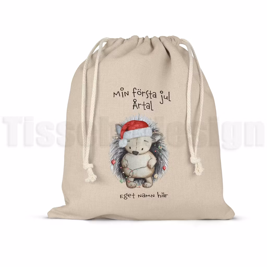 Julsäck med igelkott i tomteluva och texten Min första jul