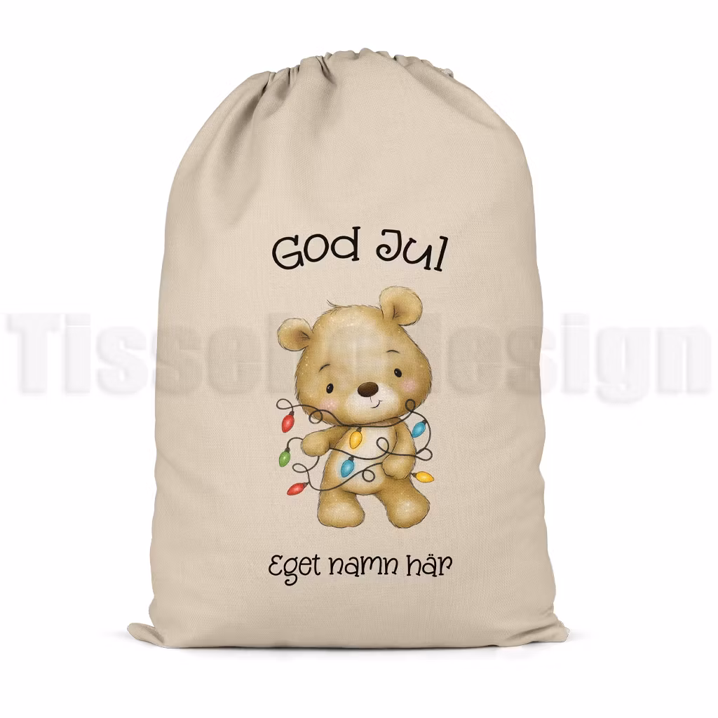 Julsäck i naturfärg med motiv av nalle som håller julgransslinga samt texten God Jul och plats för valfritt namn