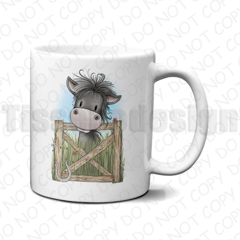 Mugg med häst som kikar fram bakom en trägrind med små blommor och hästsko