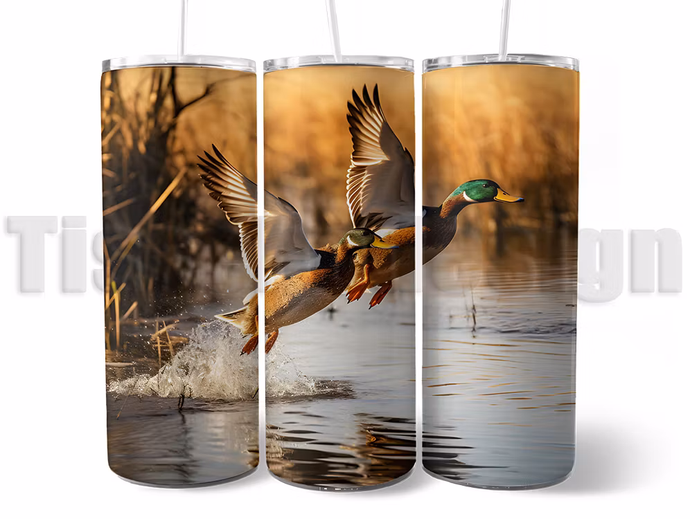 Tumbler - termomugg med motiv av flygande änder över vattnet, isolerad för varma och kalla drycker, med sugrör och rengöringsborste.