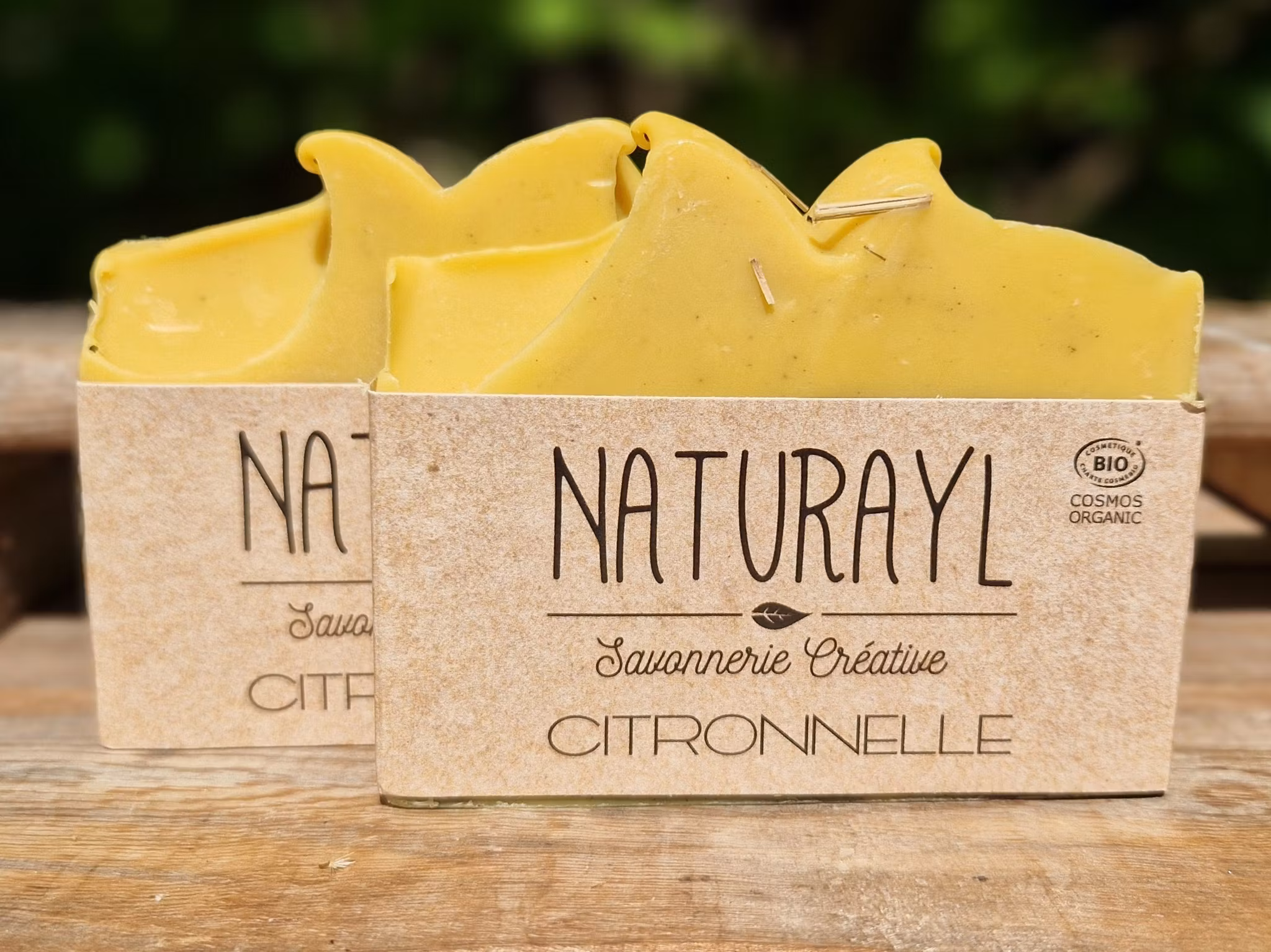 Två gula skurna tvålar med inslag av svart marmorering längst ner på tvålen, med etikett