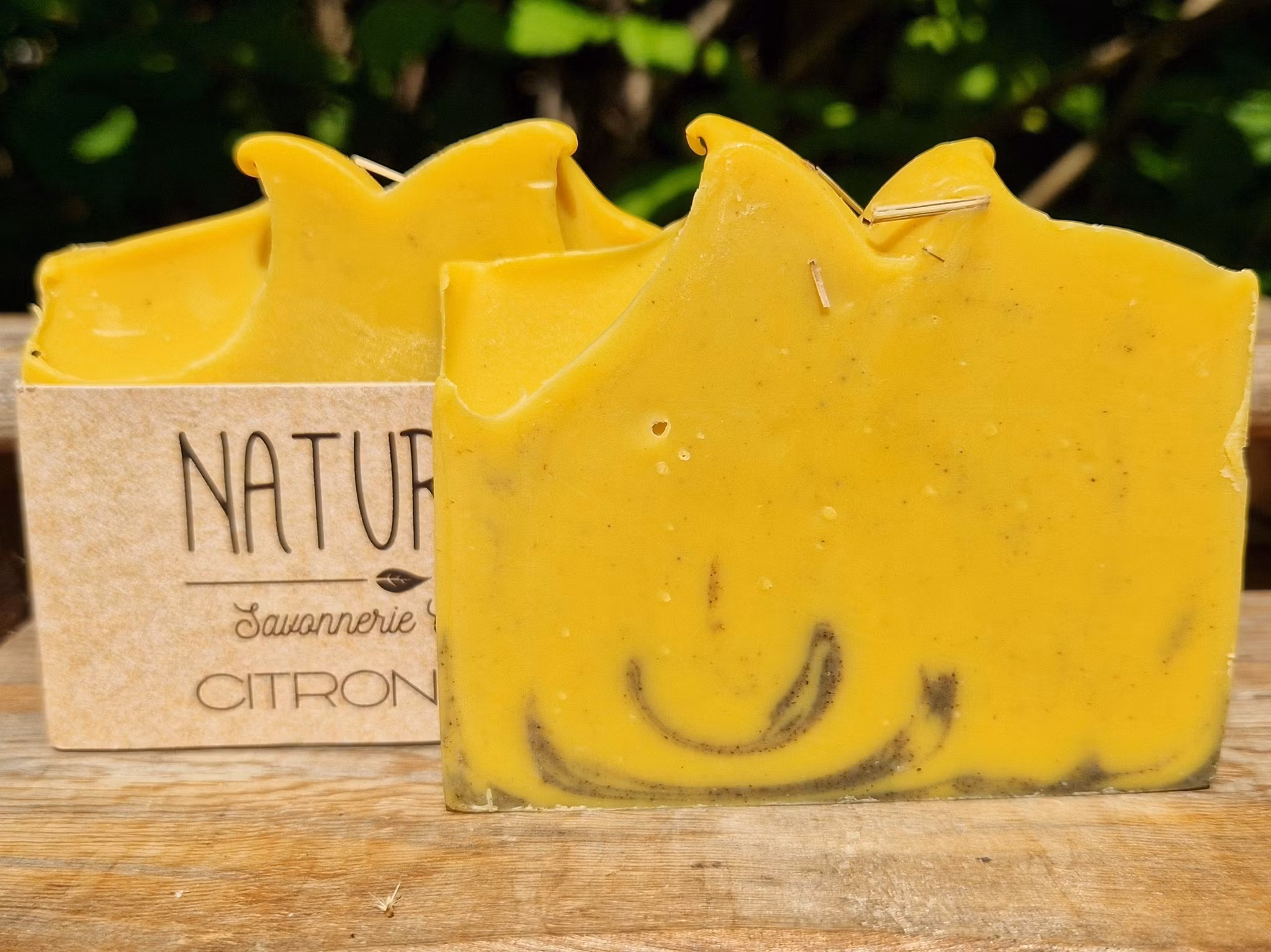 Två gula skurna tvålar med inslag av svart marmorering längst ner på tvålen, en utan etikett