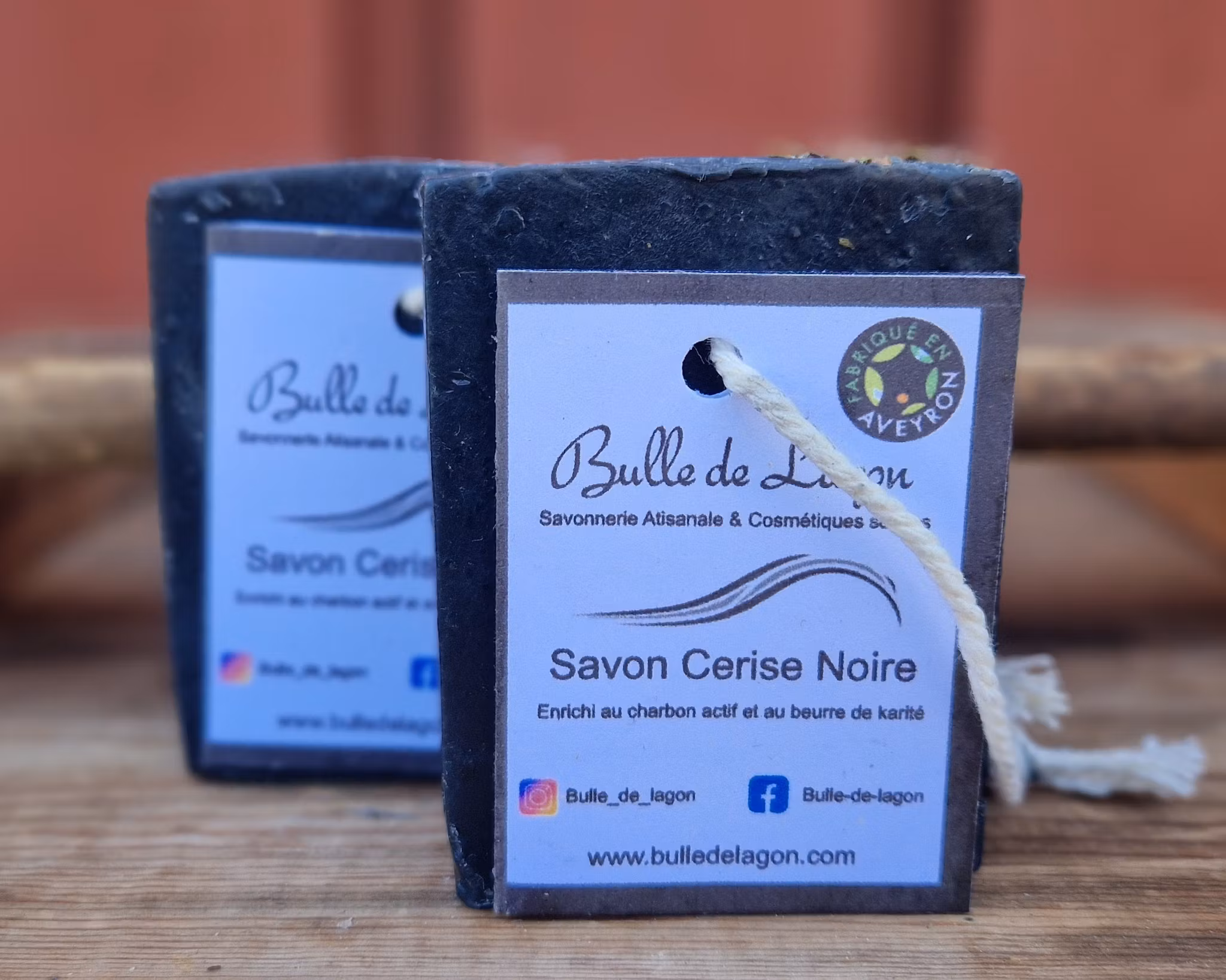 Två svarta rektangulära tvålar med etikett och snöre för upphängning