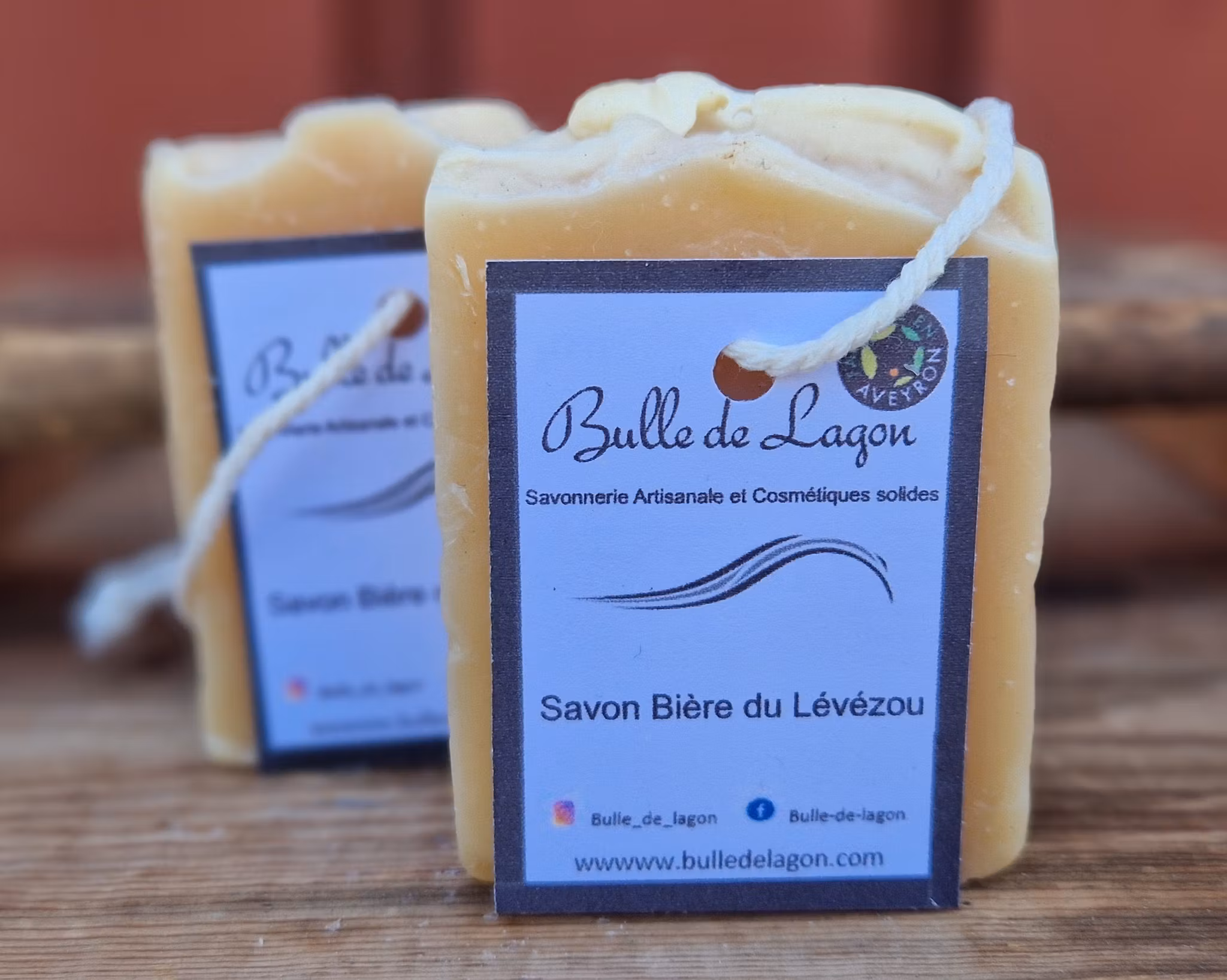 Två ljust gulvita rektangulära tvålar med etikett och snöre för upphängning