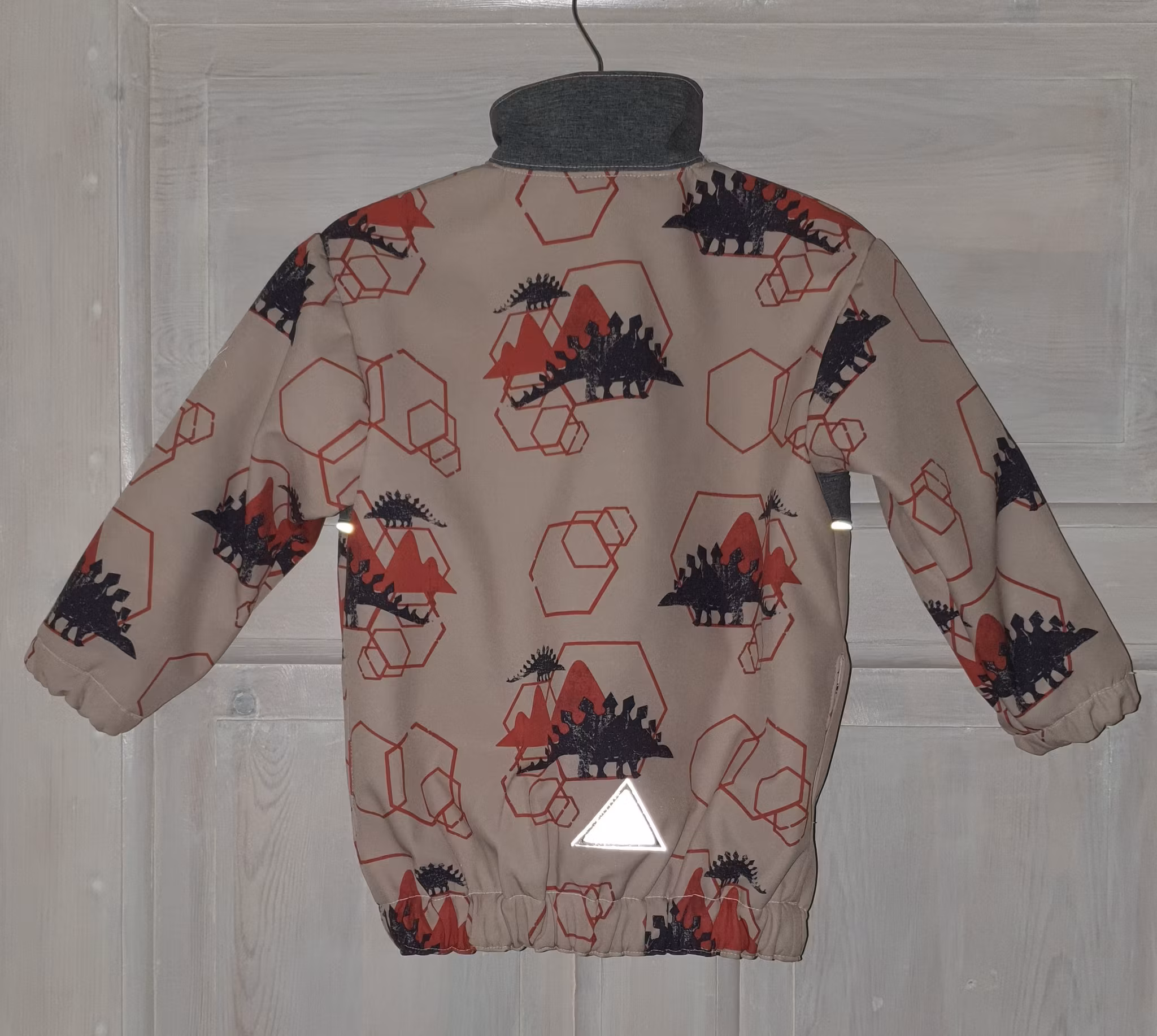 Bilden föreställer en Softshell jacka med dinosarius för barn.