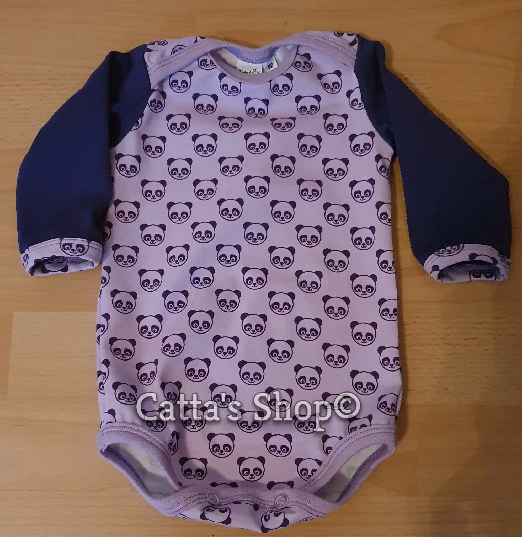 Bilden föreställer en babybody med huvud av panda i ekologisk trikå.