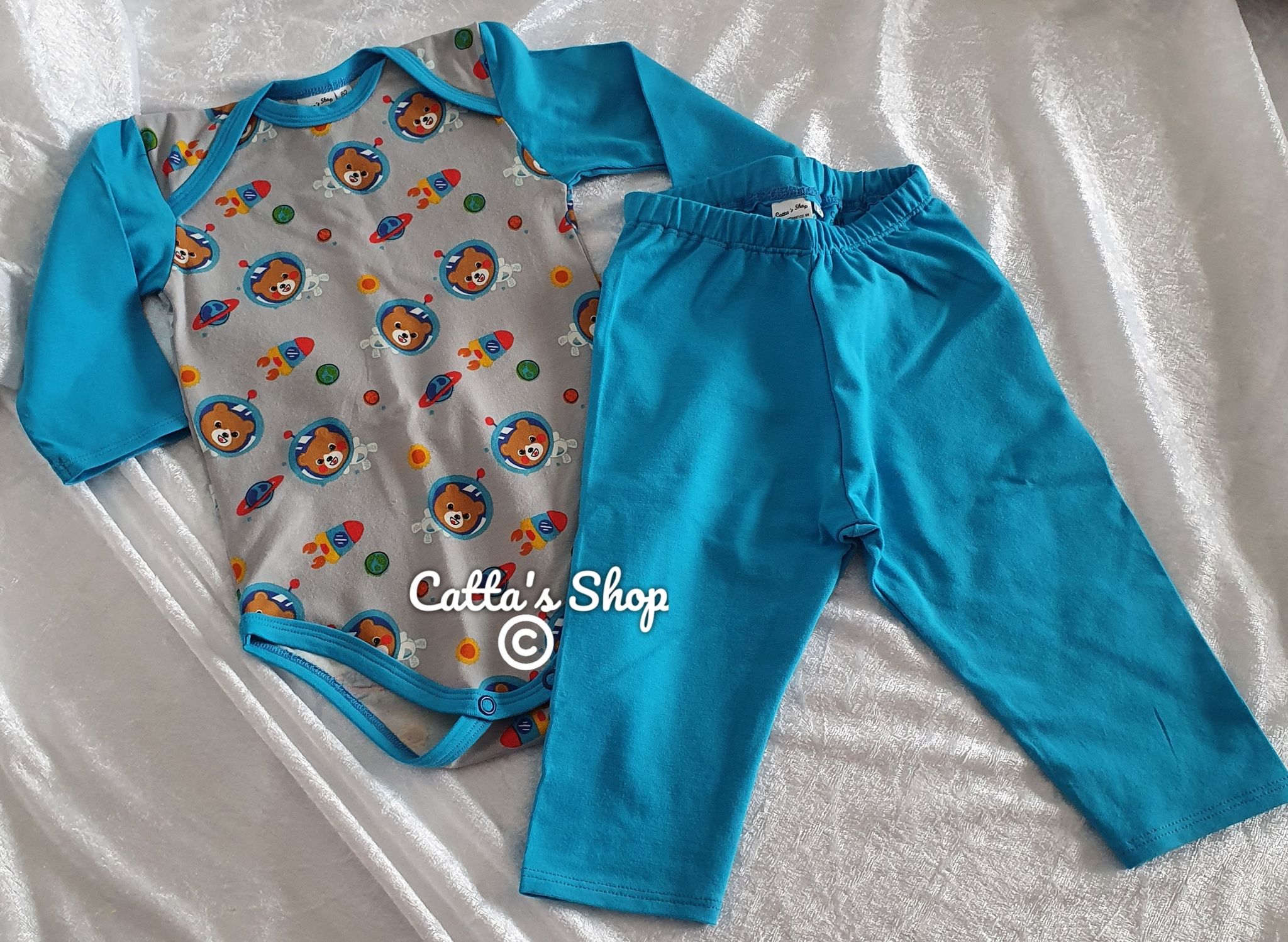 Bilden föreställer babybody med motiv rymdnallar och enfärgade byxor röd sydd i ekologisk jersey.