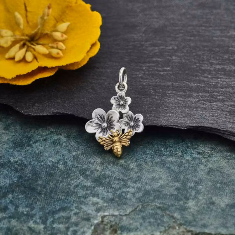 Hänge i silver med tre stycken körsbärsblommor samt ett litet bi i brons.