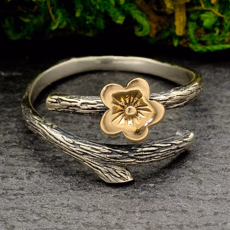 Ring i silver som föreställer en gren med en körsbärsblomma i brons på.
