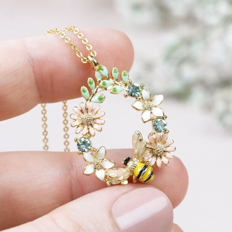 Bild på ett halsband i form av en droppformad blomsterkrans med ett litet bi