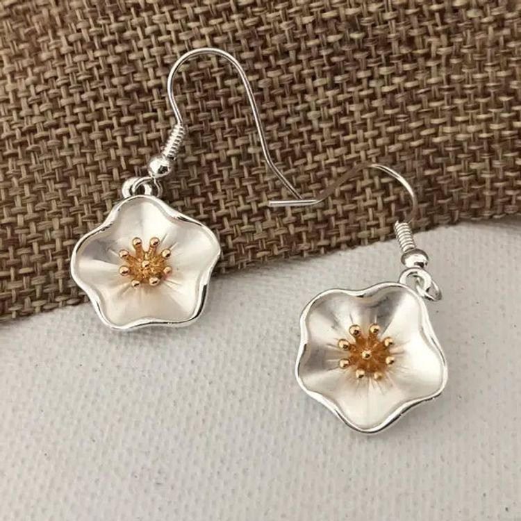Örhängen med hibiskusblomma i silver- och guldfärg på krok.