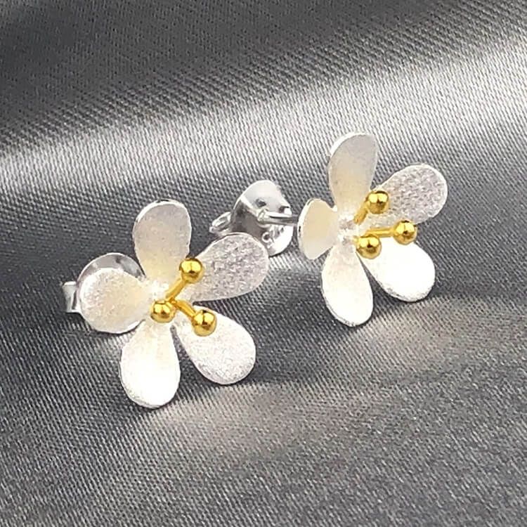 Bild på silverörhängen i form av blommor samt detaljer med guldplätering