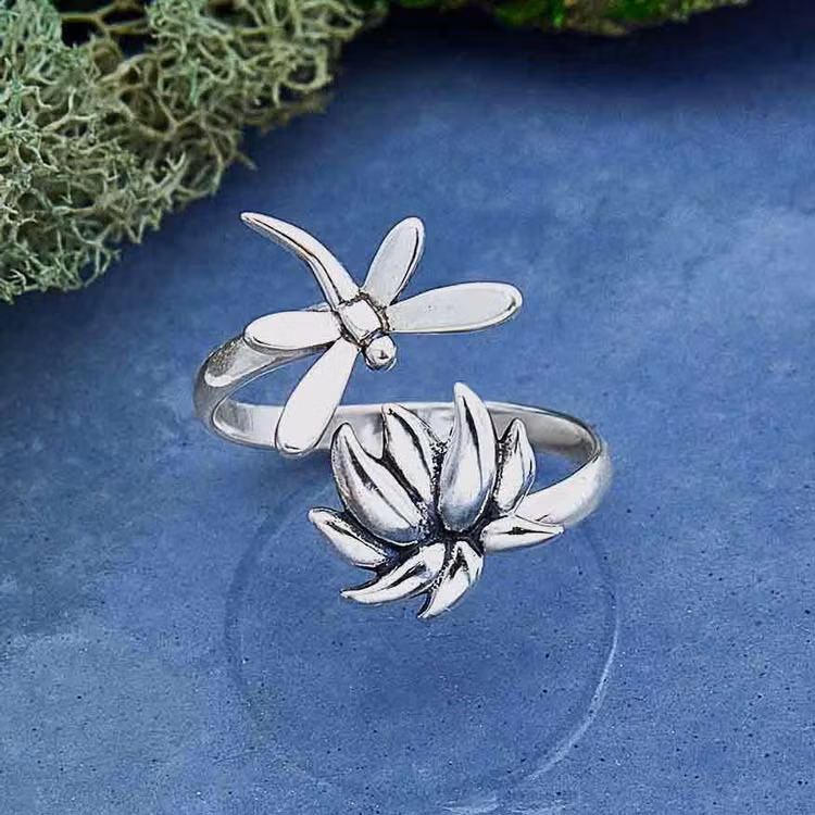 Bild på en silverring med en trollslända samt en lotusblomma.