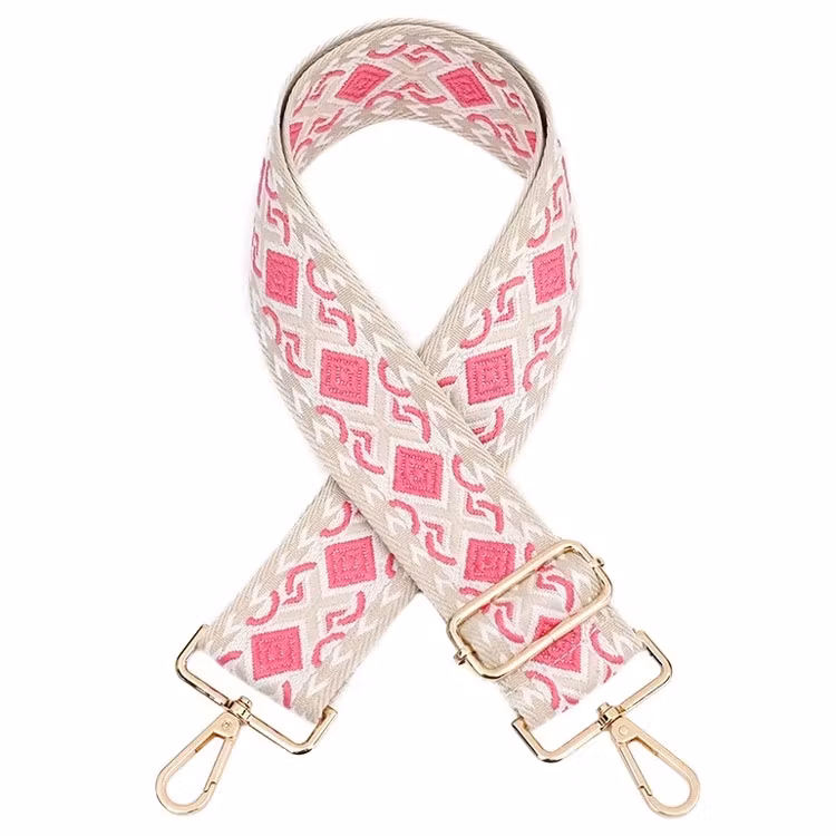 Bild på en bred axelrem till väska med mönster i rosa och beige färger.